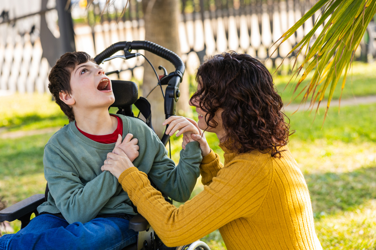 playing with son with disability in wheelchair outdoors